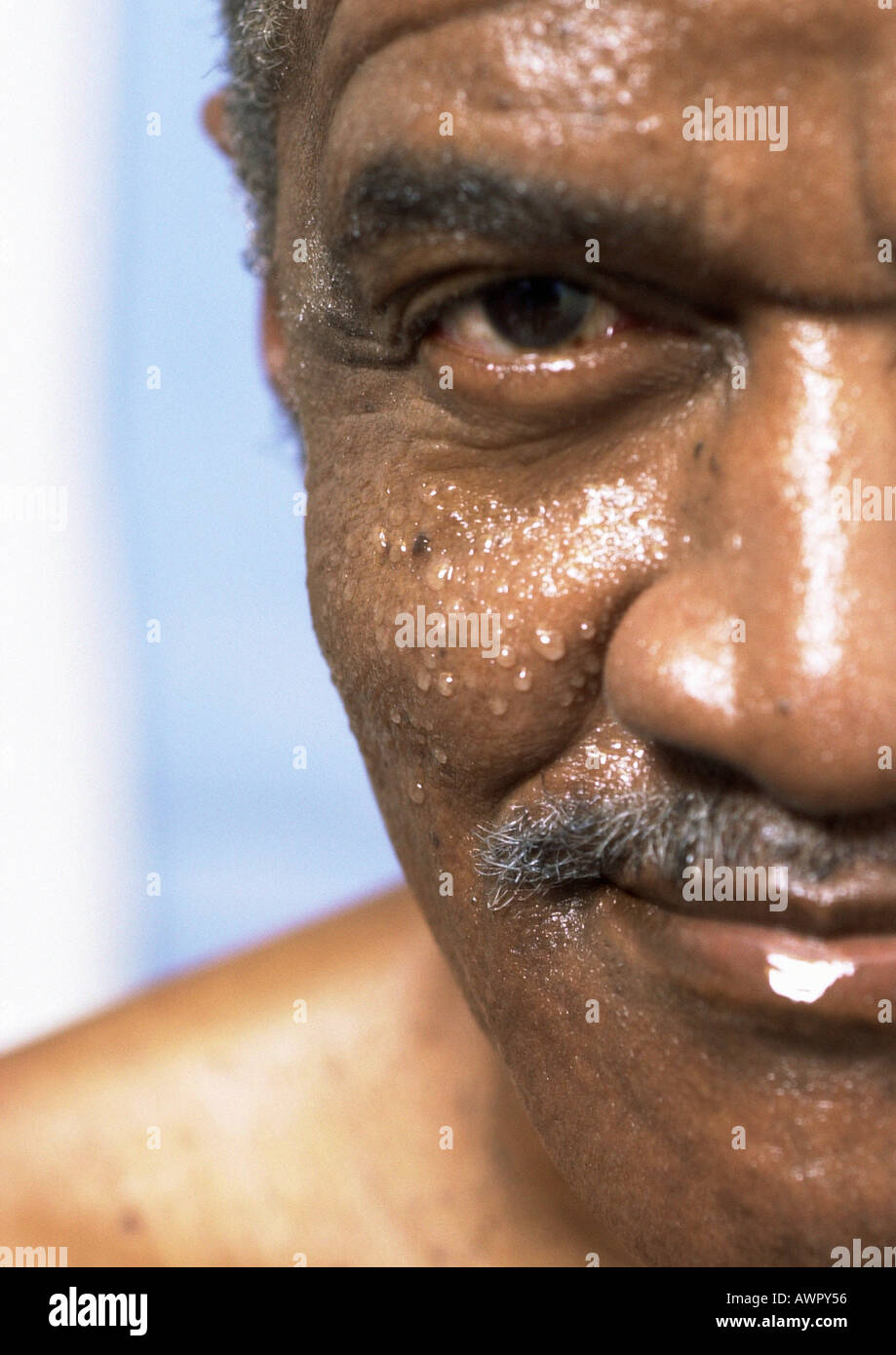 L'uomo anziano con il viso bagnato cercando nella fotocamera, close-up di un lato della faccia. Foto Stock