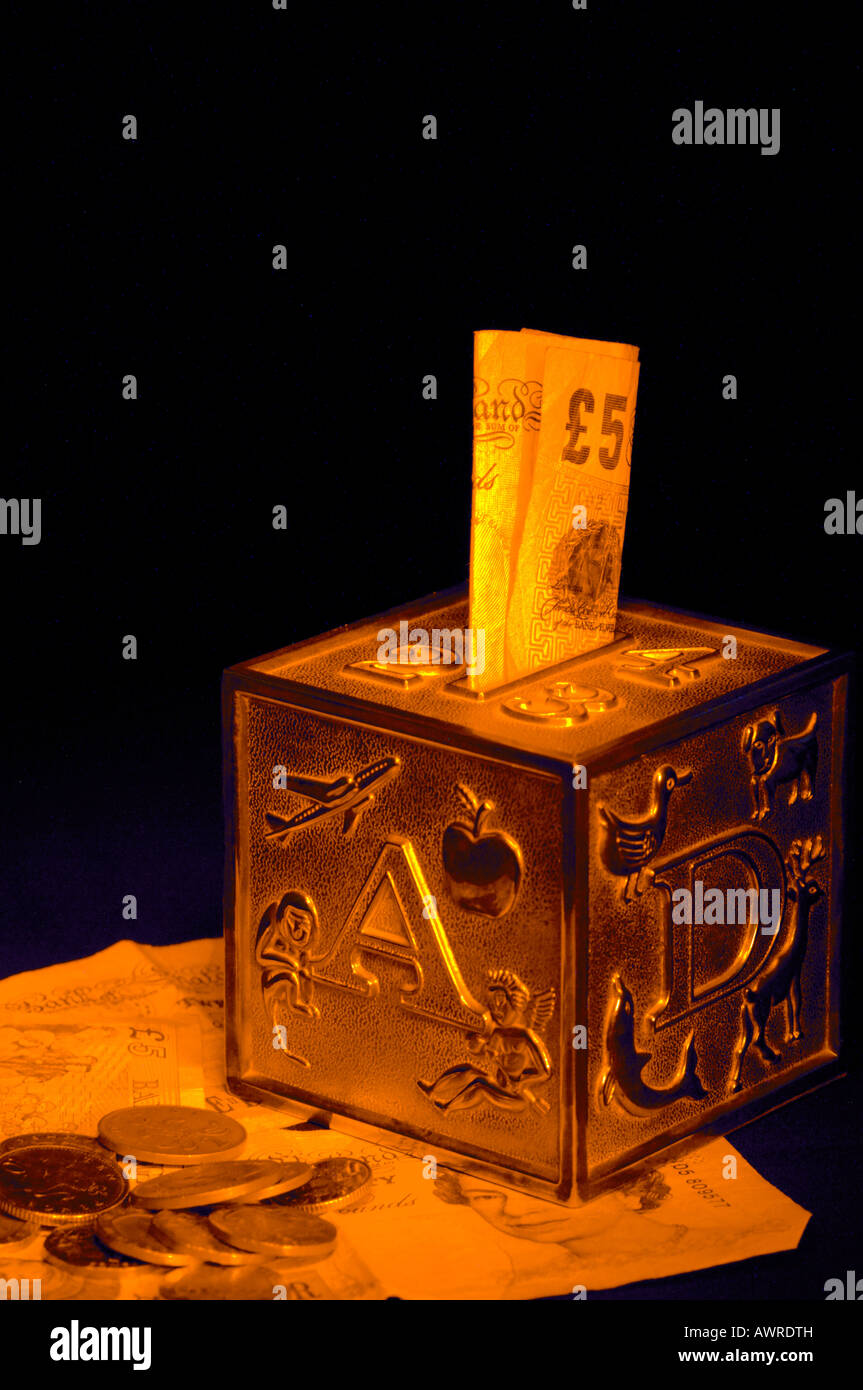 Un childrens mony box che mostra l'Alfabeto si fermò in appoggio su varie denominazioni del Regno Unito british crrencey con un 5 a 5 libbre Foto Stock
