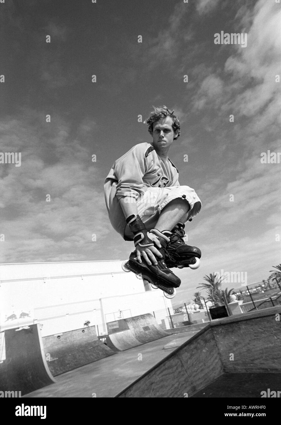 Giovane uomo su skateboard, saltando, mid-aria. Foto Stock