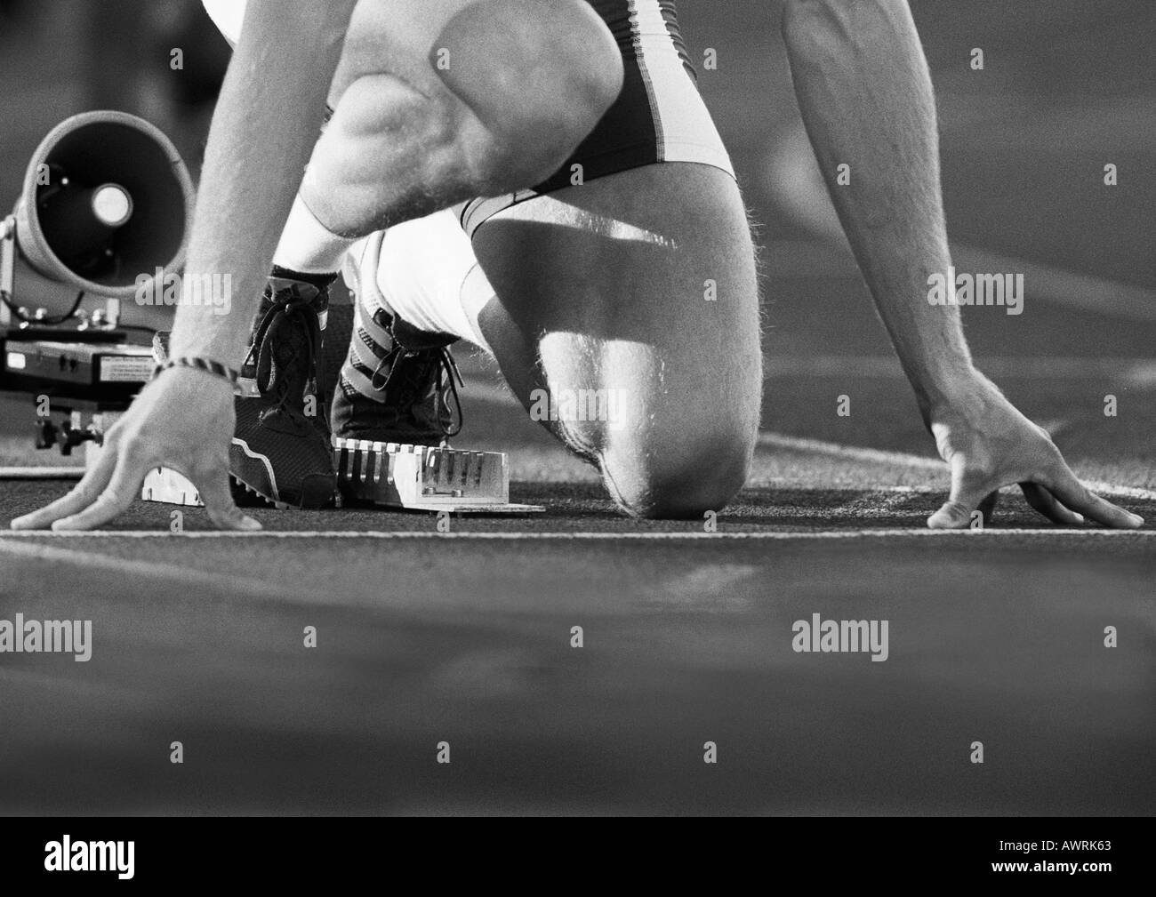 Runner maschio nel blocco di partenza a basso angolo di visione, close-up, b&W Foto Stock