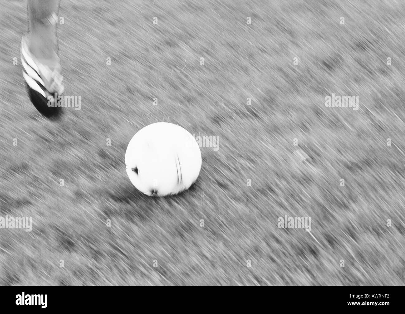 Piede del giocatore e pallone da calcio, offuscata, b&w. Foto Stock