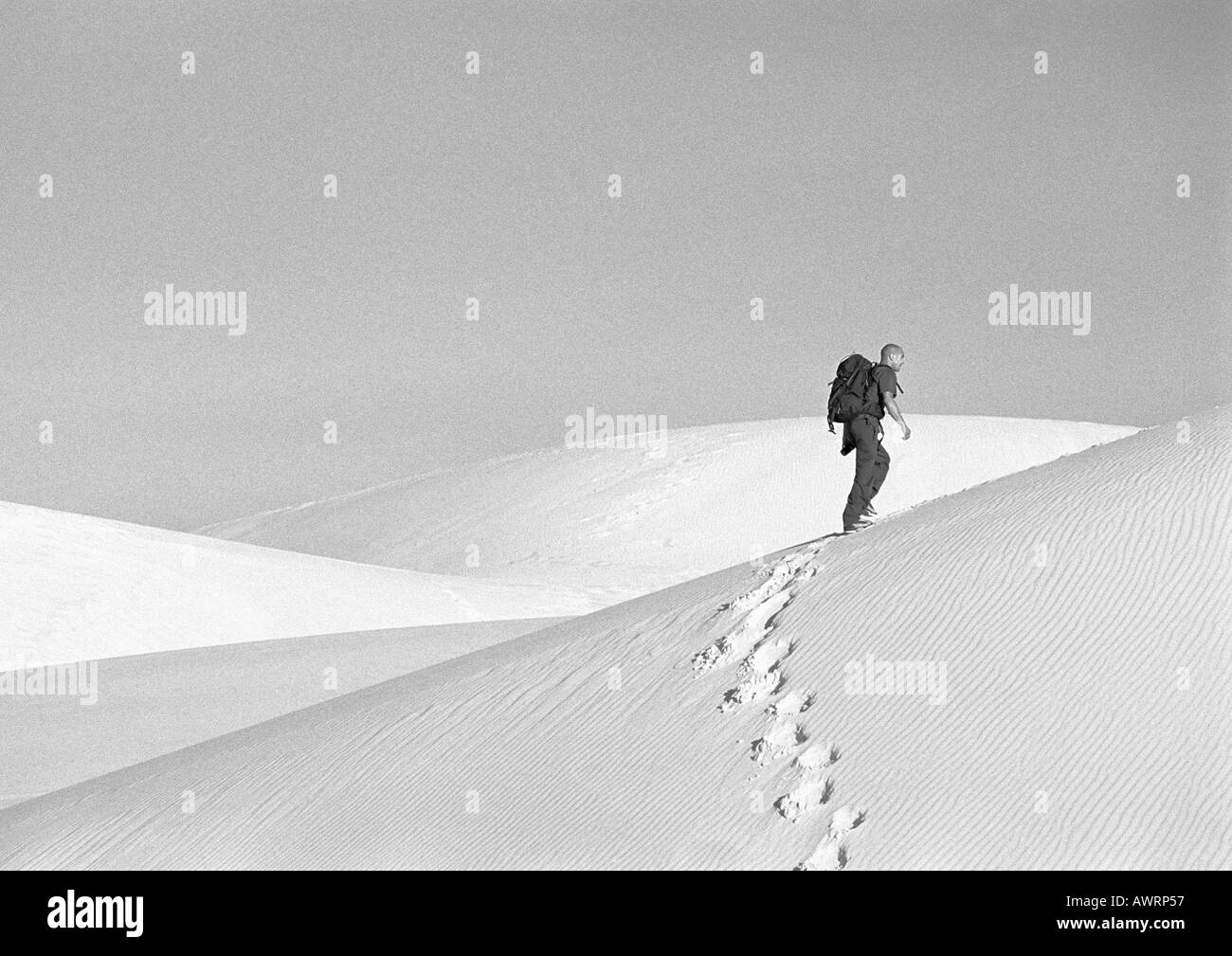 Uomo che passeggia tra le dune, vista laterale, b&W Foto Stock
