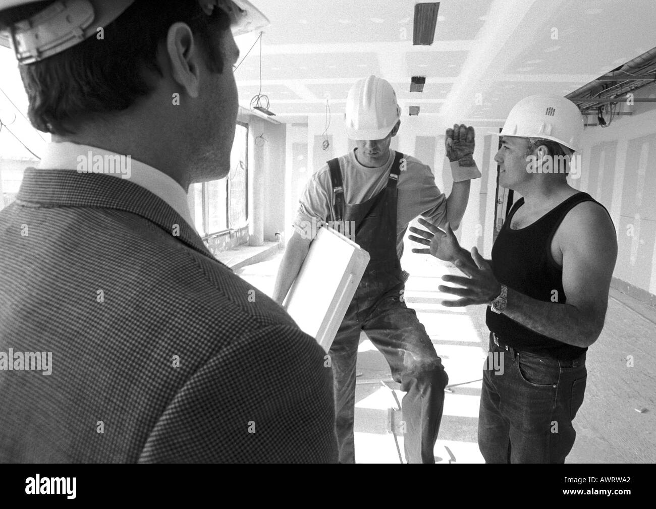 Uomini che indossano copricapi rigidi, parlando, b&W Foto Stock