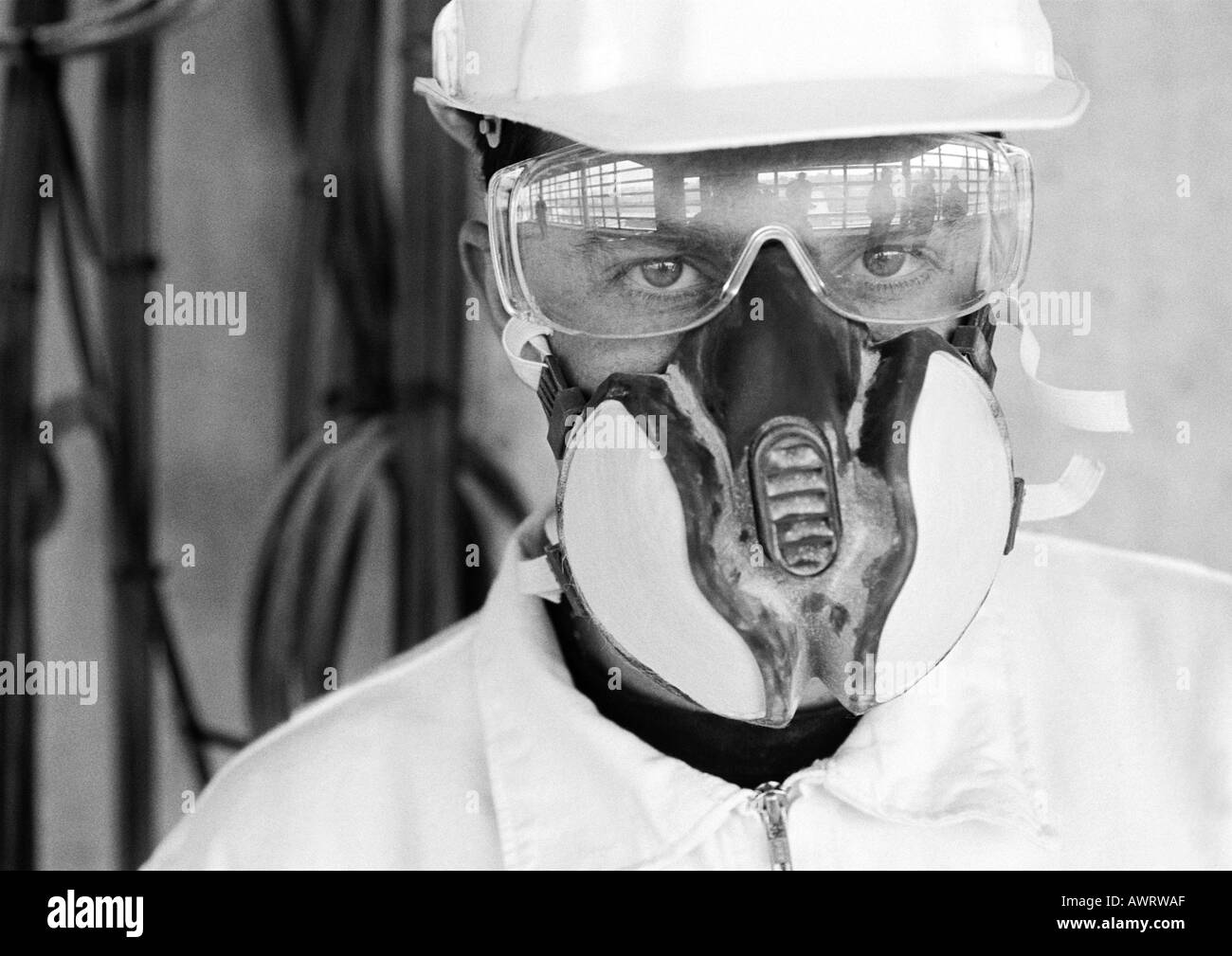 Uomo che indossa elmetto, una maschera antipolvere e bicchieri, close-up, b&W Foto Stock