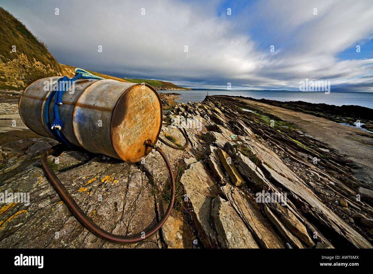 Svuotare barile di petrolio sulle rocce della costa atlantica West Cork in Irlanda Foto Stock
