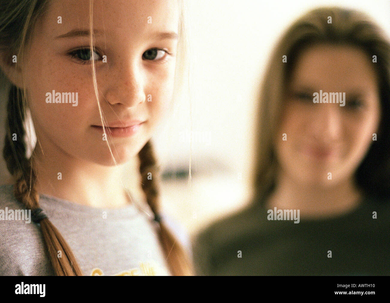 Due ragazze, più giovane ragazza in primo piano la ragazza più vecchi sfocati sullo sfondo, ritratto Foto Stock