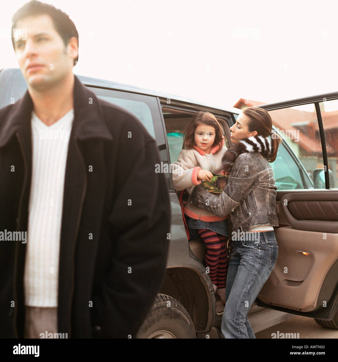 Madre figlia di arrivare fuori di auto, il padre a piedi Foto Stock