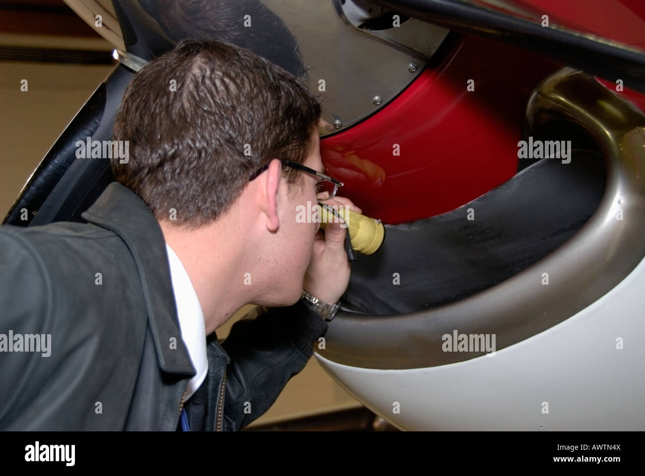 Un pilota fa un controllo di preflight del motore di aspirazione dell'aria,accertandosi che non vi siano ostruzioni. Foto Stock