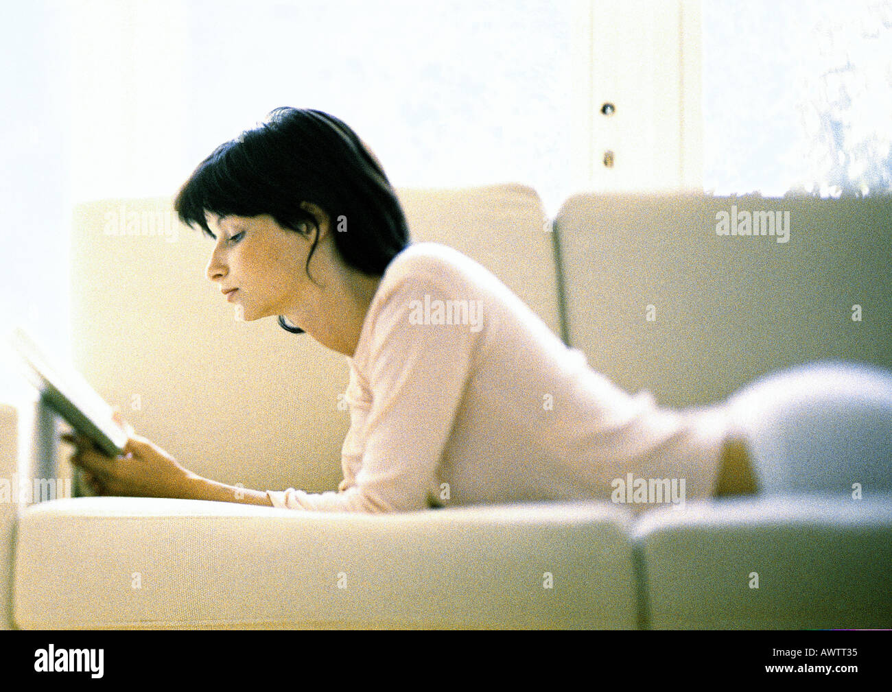 Donna sdraiata sul divano, lettura Foto Stock