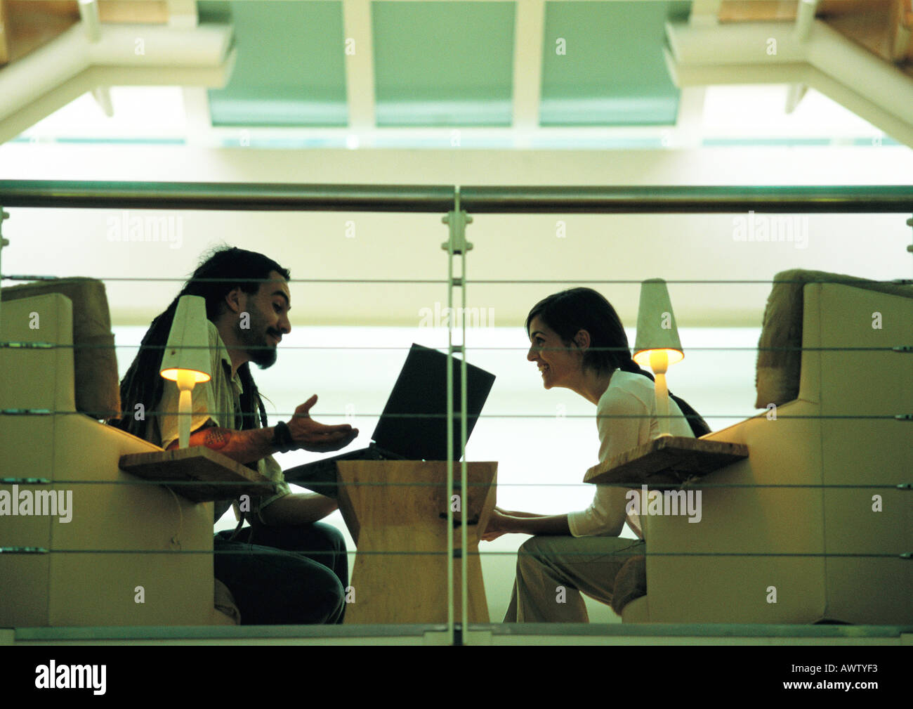 Uomo seduto e parlando con la donna, vista laterale Foto Stock