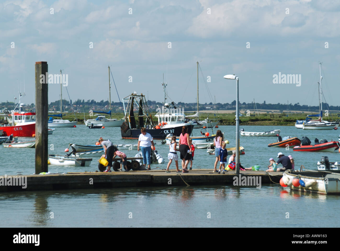 Famiglie di West Mersea che utilizzano un pontile galleggiante per la pesca delle granchi in una giornata di sole nell'Essex, Inghilterra, Regno Unito Foto Stock