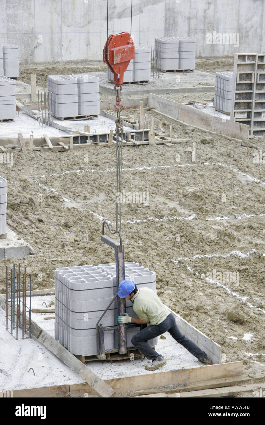 Lavoratore gru guida sollevato tavolozza di brezza blocchi sul sito di costruzione Foto Stock