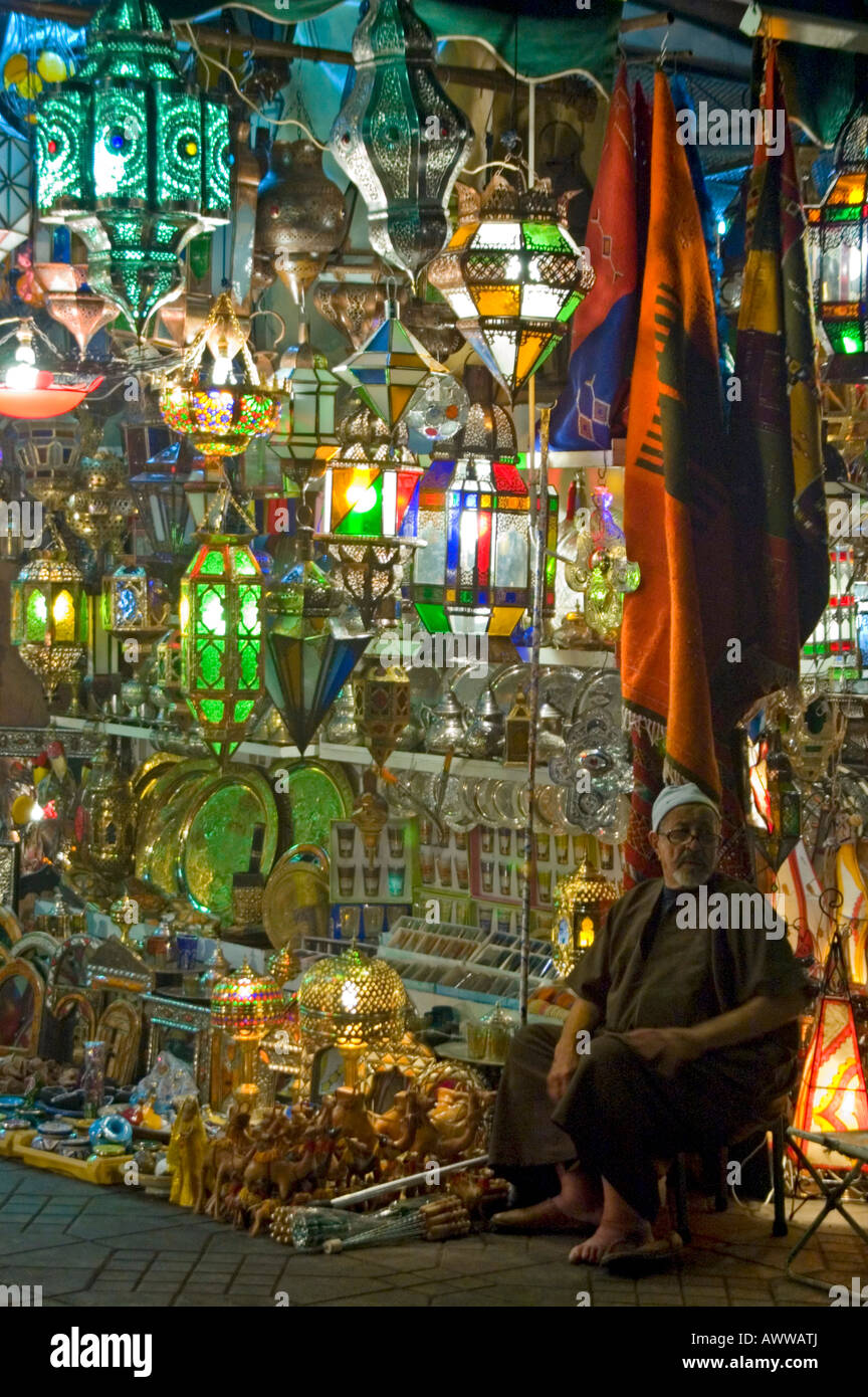 Verticale fino in prossimità di un bottegaio seduto fuori i suoi colorati negozi che vendono Marocchino tradizionale luci e lanterne di notte. Foto Stock