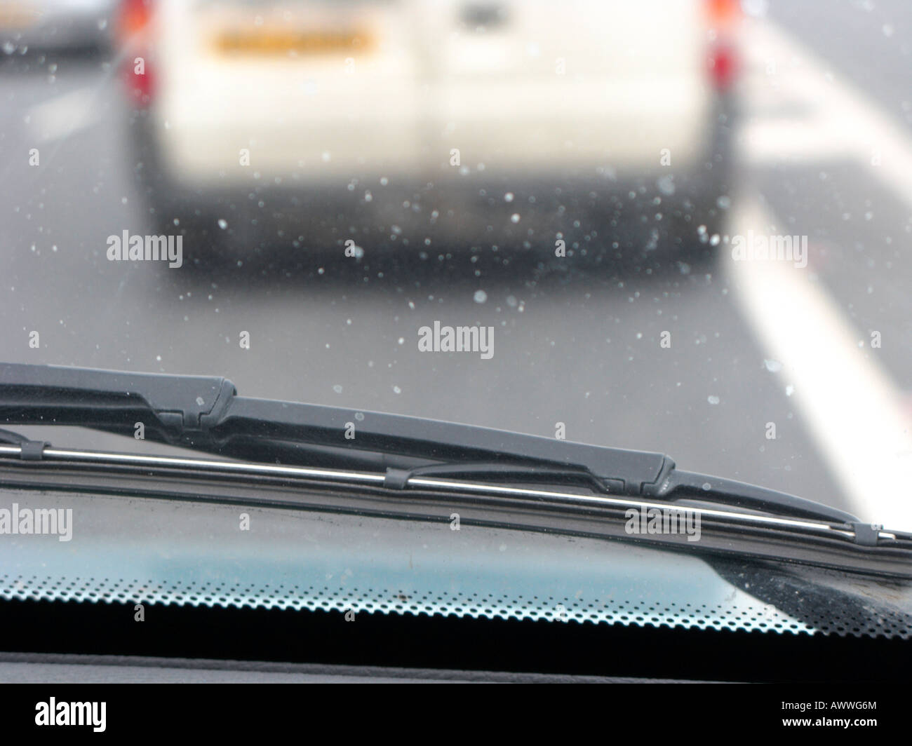 Guardando al di fuori di un automobile sopra una spazzola tergicristallo e il parabrezza sporco nel traffico Foto Stock