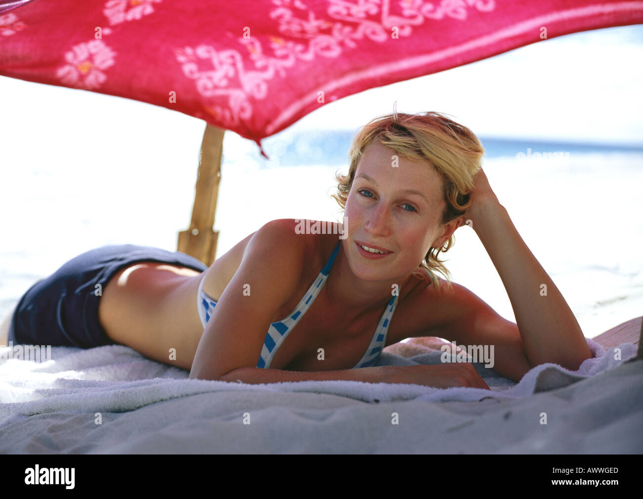Donna sdraiata sulla spiaggia sotto ombrellone Foto Stock