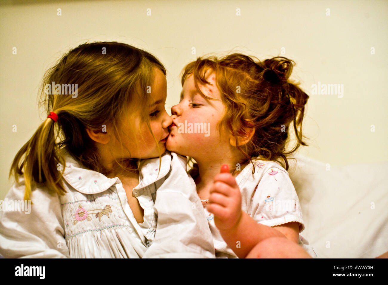 Due sorelle di tre e quattro anni di baciare buonanotte Foto Stock