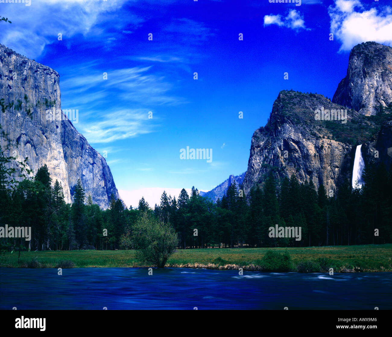 Il fiume Merced pleacefully fluisce attraverso le torreggianti scogliere di granito del Parco Nazionale di Yosemite in California Foto Stock