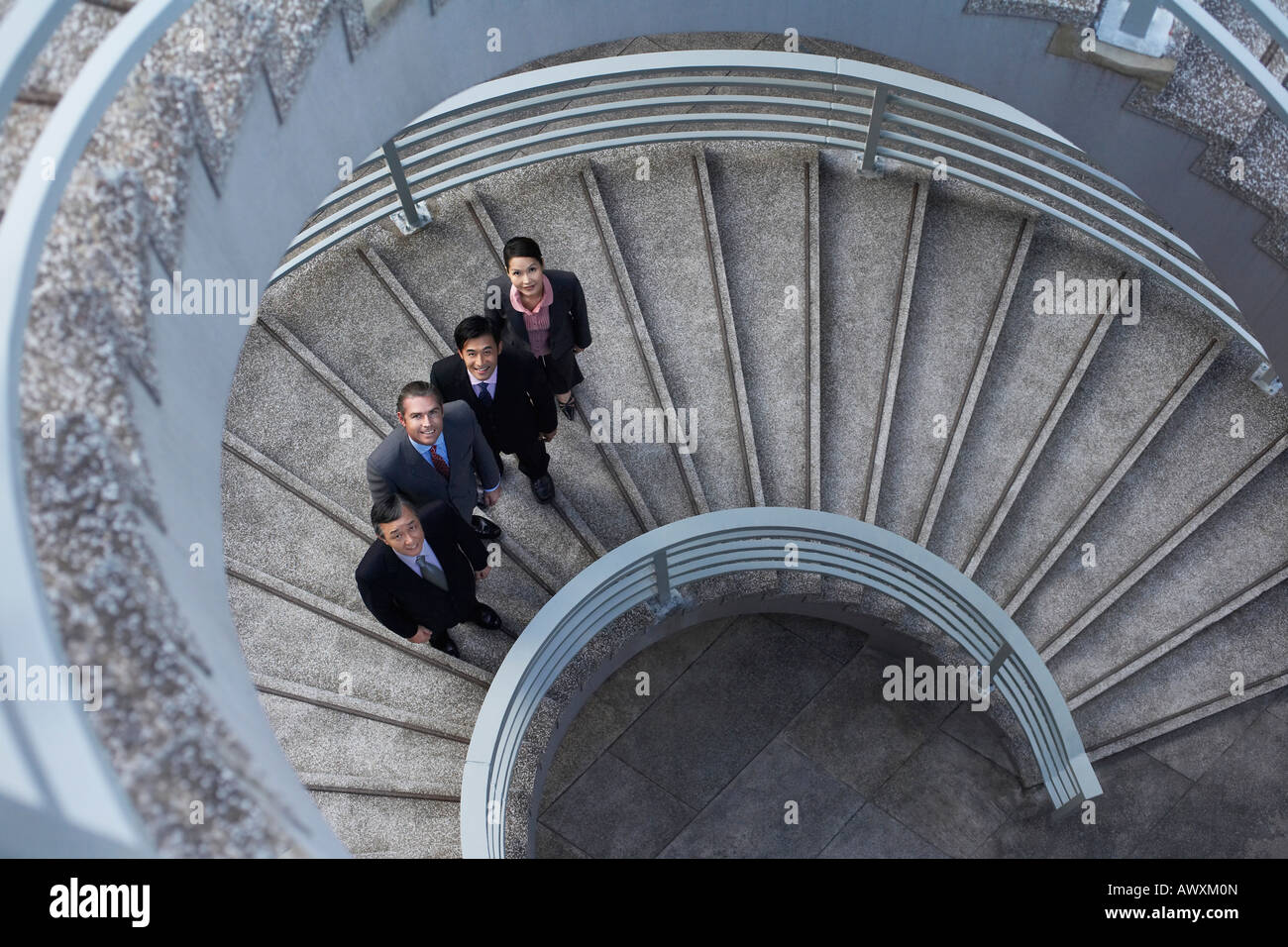 Quattro soci di affari in piedi su una scalinata a spirale, ritratto Foto Stock