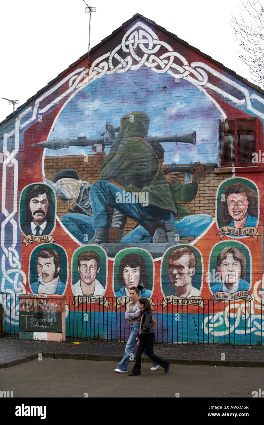 Due giovani donne a piedi passato un IRA di paramilitari memorial murale dotata di RPG e IRA sniper nei mercati zona di Belfast Foto Stock