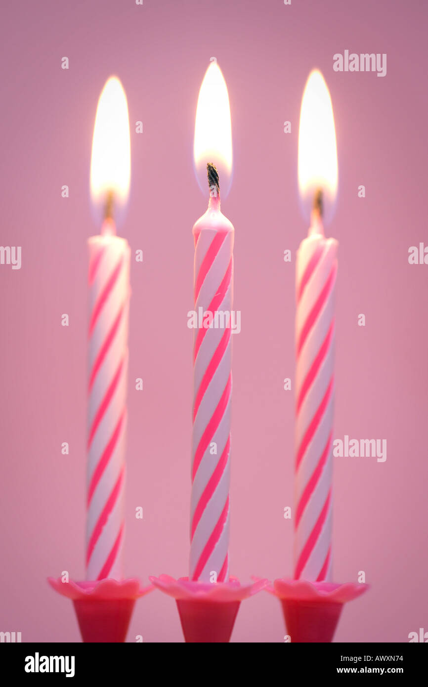 Tre candele compleanno su sfondo rosa Foto Stock