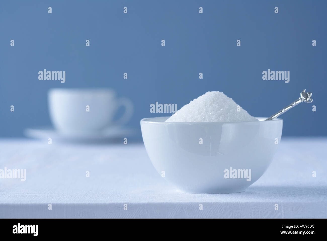 Ciotola di zucchero sul tavolo, tazza da tè in background Foto Stock