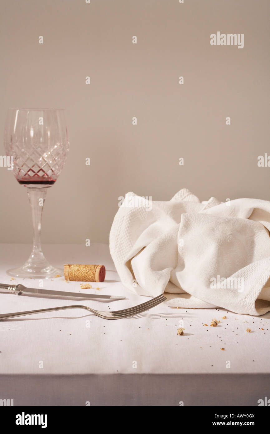 Bicchiere da vino, posate, canovaccio sul tavolo disordinato Foto Stock