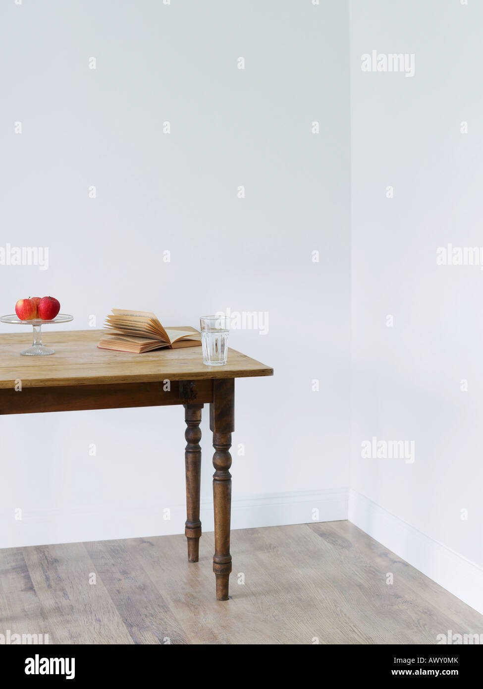 Bicchiere di acqua, libro e le mele sulla tavola in camera Foto Stock