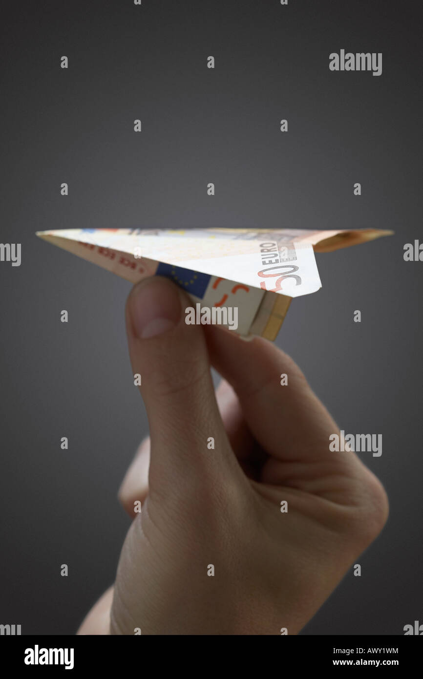 Persona in possesso di aeroplano di carta fatta di 50 euro nota, close-up di mano Foto Stock