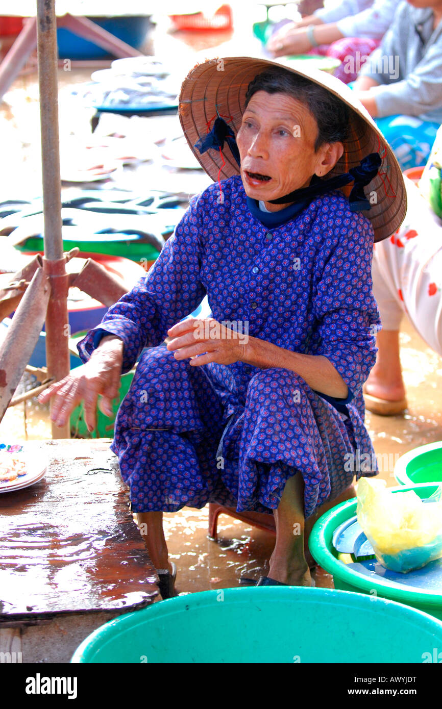 Asia far East Vietnam , Hoi An mercato , emaciato vecchia donna in non bai Tho , dipendente a foglie di coleottero , vendendo tagliatelle da pavimentazione stalla Foto Stock