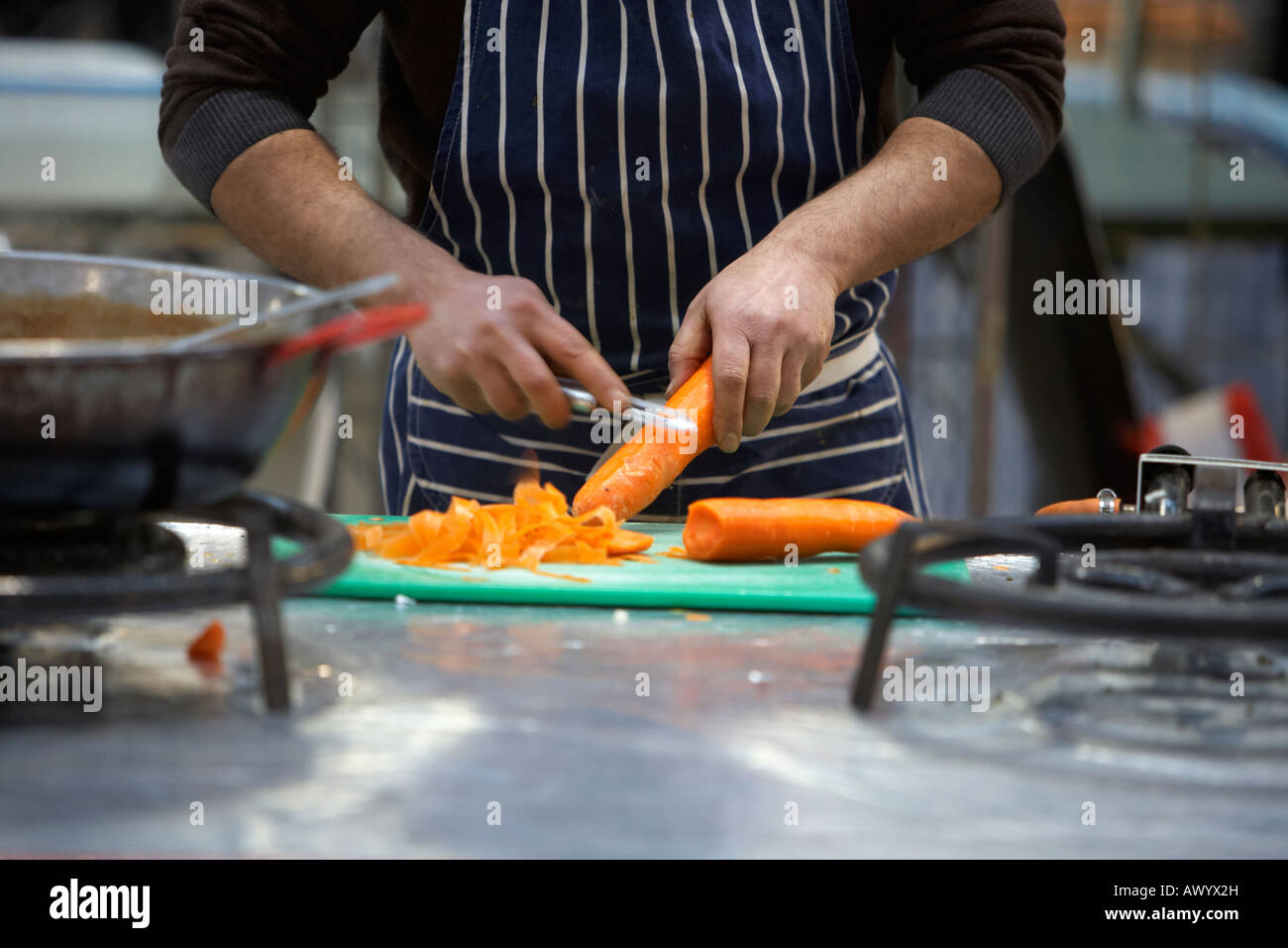 Lo chef peeling pelare le carote sul mercato indiano in stallo il mercato coperto Foto Stock