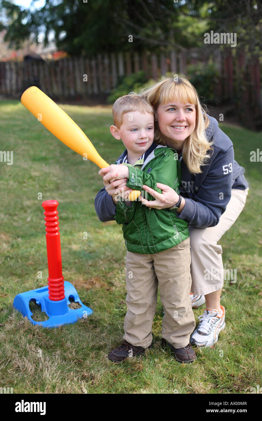 Madre aiutare giovane figlio swing di plastica di una mazza da baseball Foto Stock