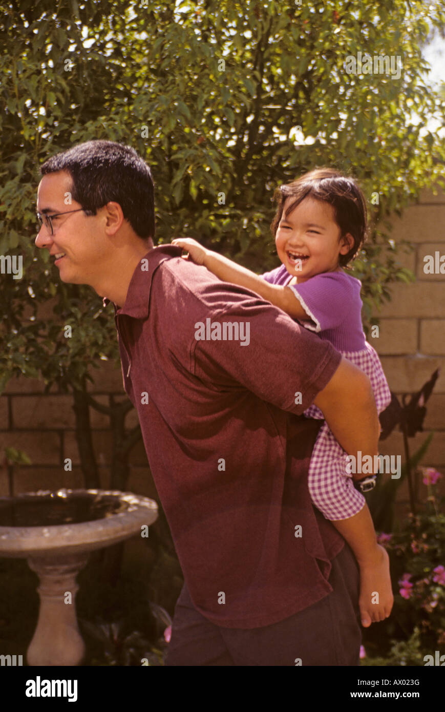 Americana giapponese padre dà la figlia una piggy back ride come lei ride Foto Stock