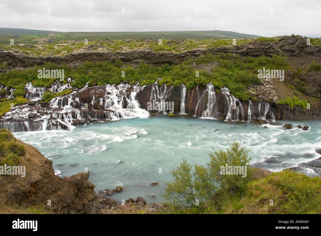 Fiume Hvita invia acqua glaciale fluente attraverso strati di campo di lava a cascata Hraunfossar Islanda Europa Foto Stock