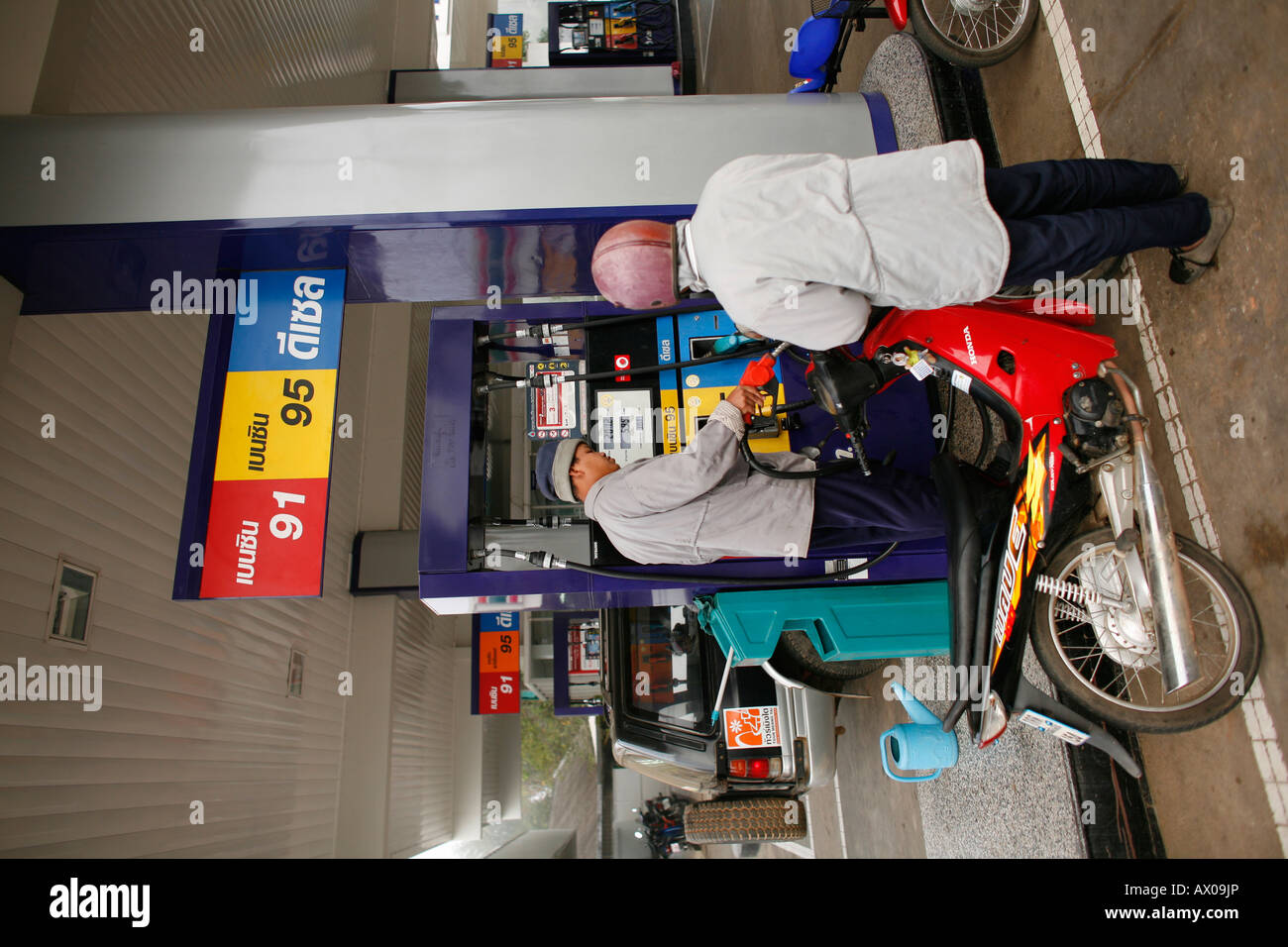 Il conducente di un ciclomotore riempie il serbatoio di benzina a una grande stazione di servizio in Bangkok Foto Stock