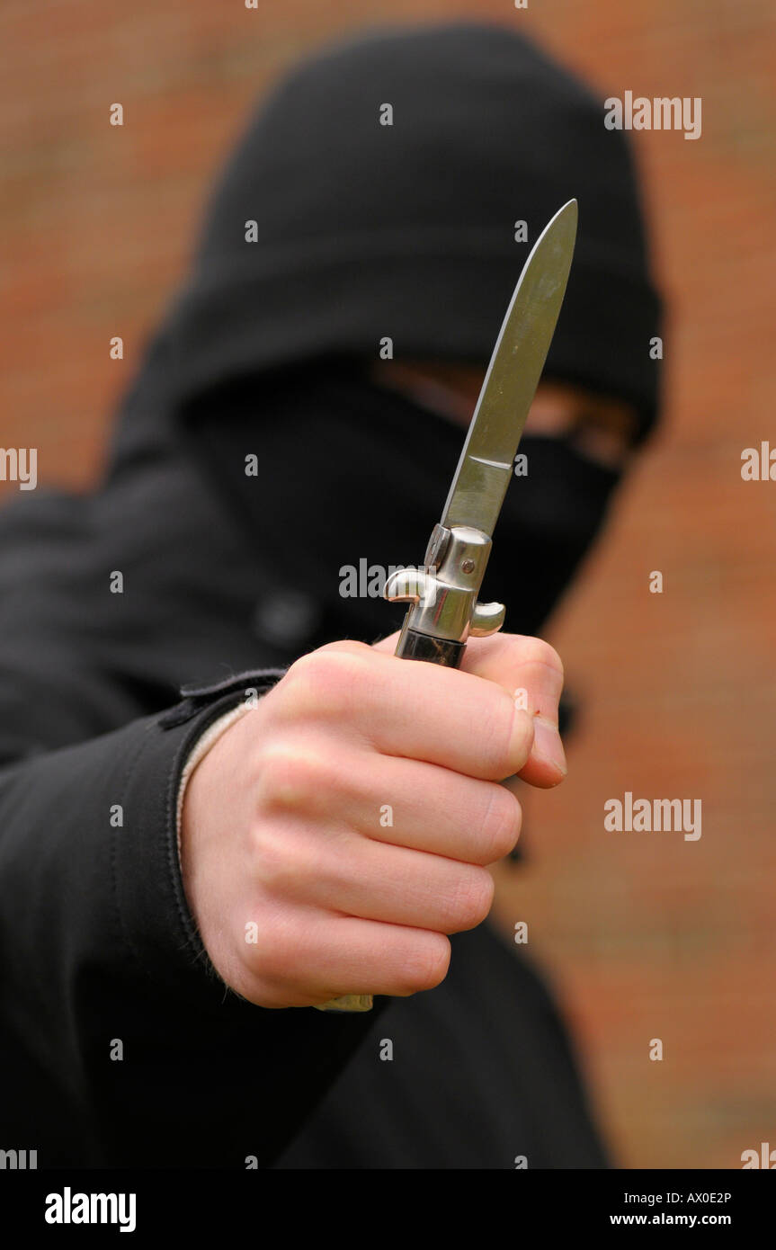 Giovane uomo con il viso coperto brandendo un coltello Foto Stock
