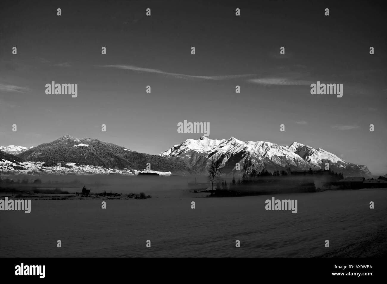 Panorarama paesaggio montagna in inverno con nebbia bassa e piccola fattoria liscio cielo blu e smallnes cloud in nero e bianco Foto Stock