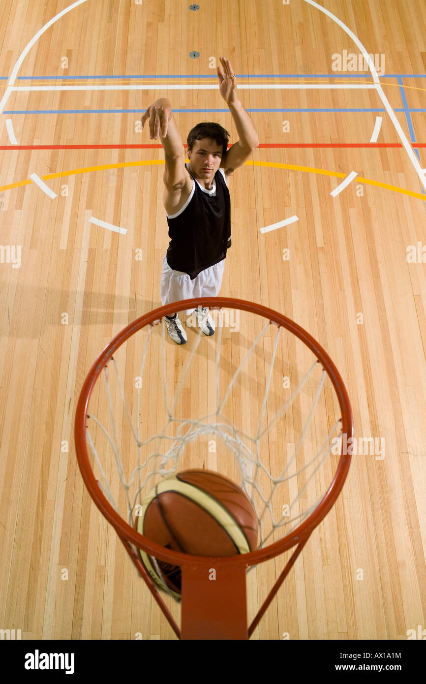 Un giovane uomo di ripresa di un basket in un Basketball hoop Foto Stock