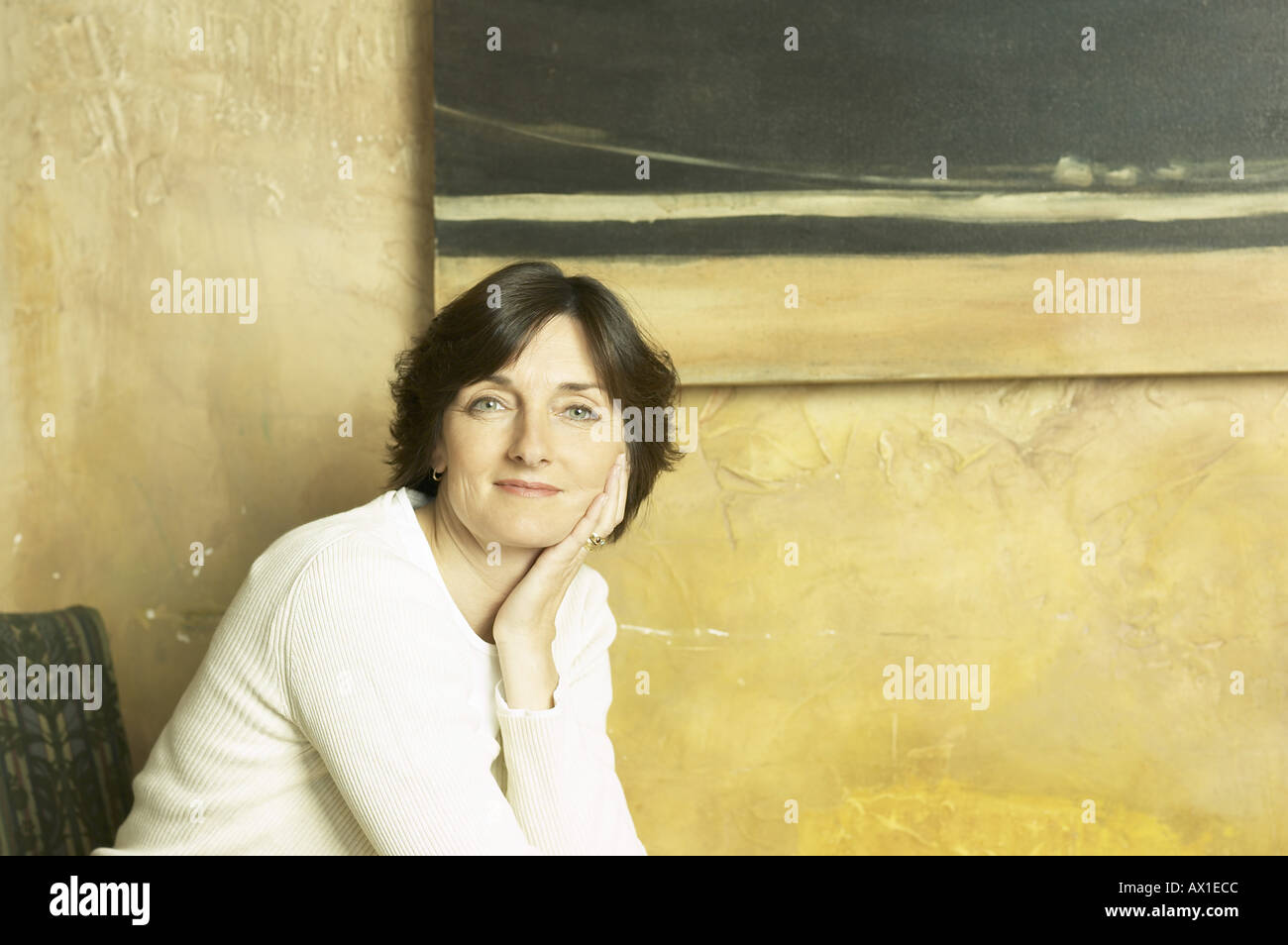 Donna sorridente seduto contro il muro di pietra Foto Stock