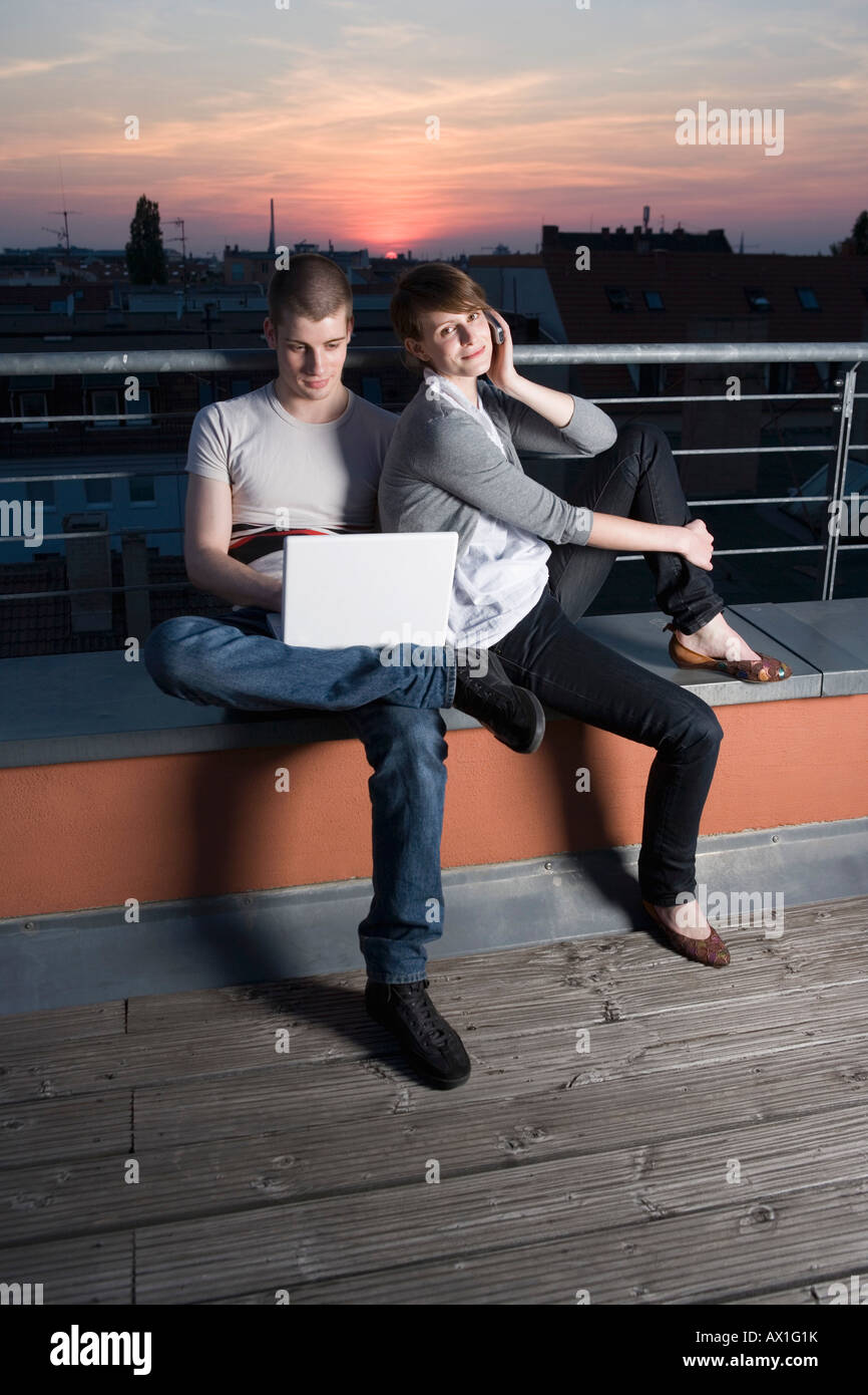 Una giovane coppia con un computer portatile su una terrazza sul tetto Foto Stock