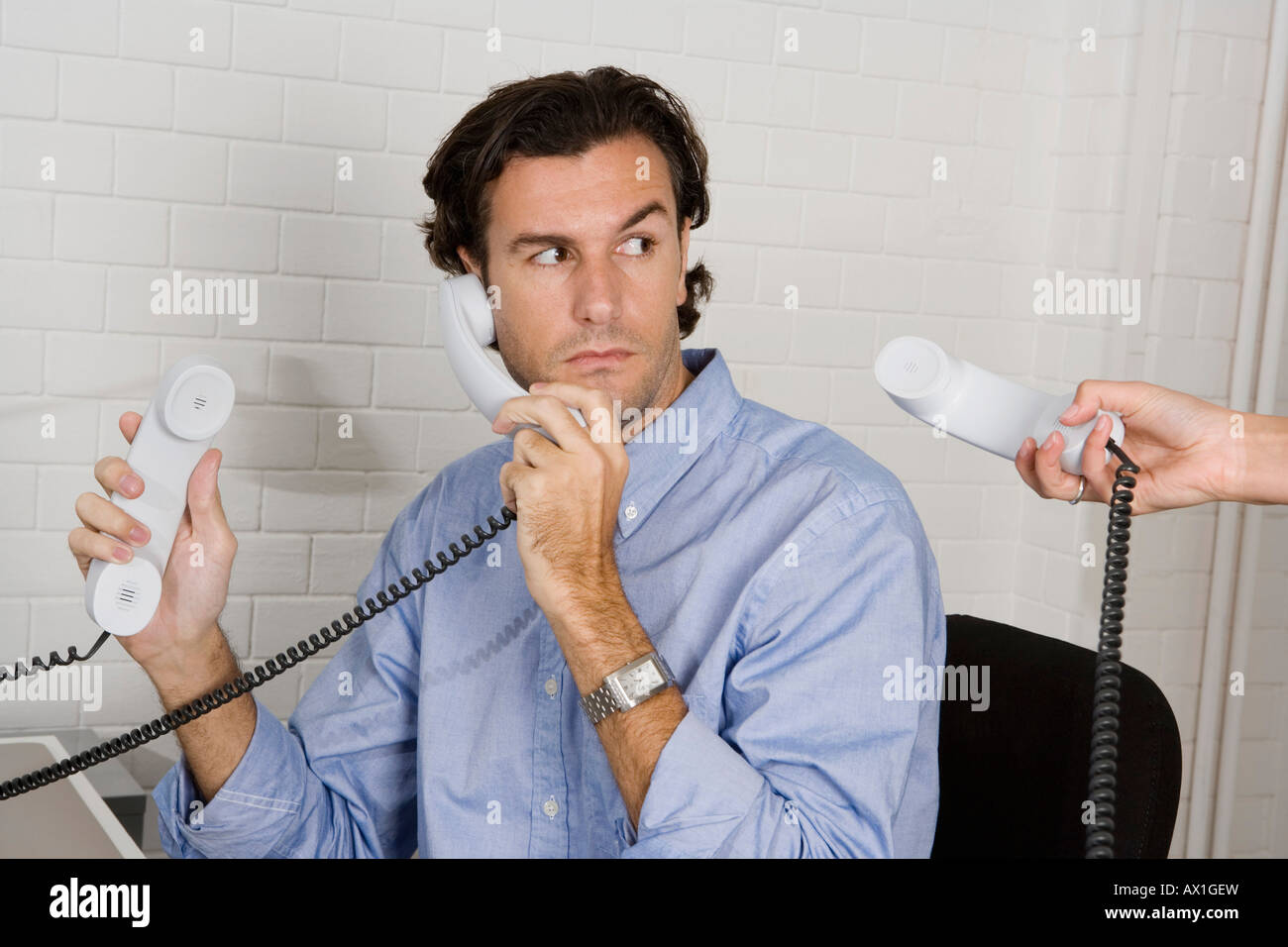 Un imprenditore con tre ricevitori telefonici Foto Stock