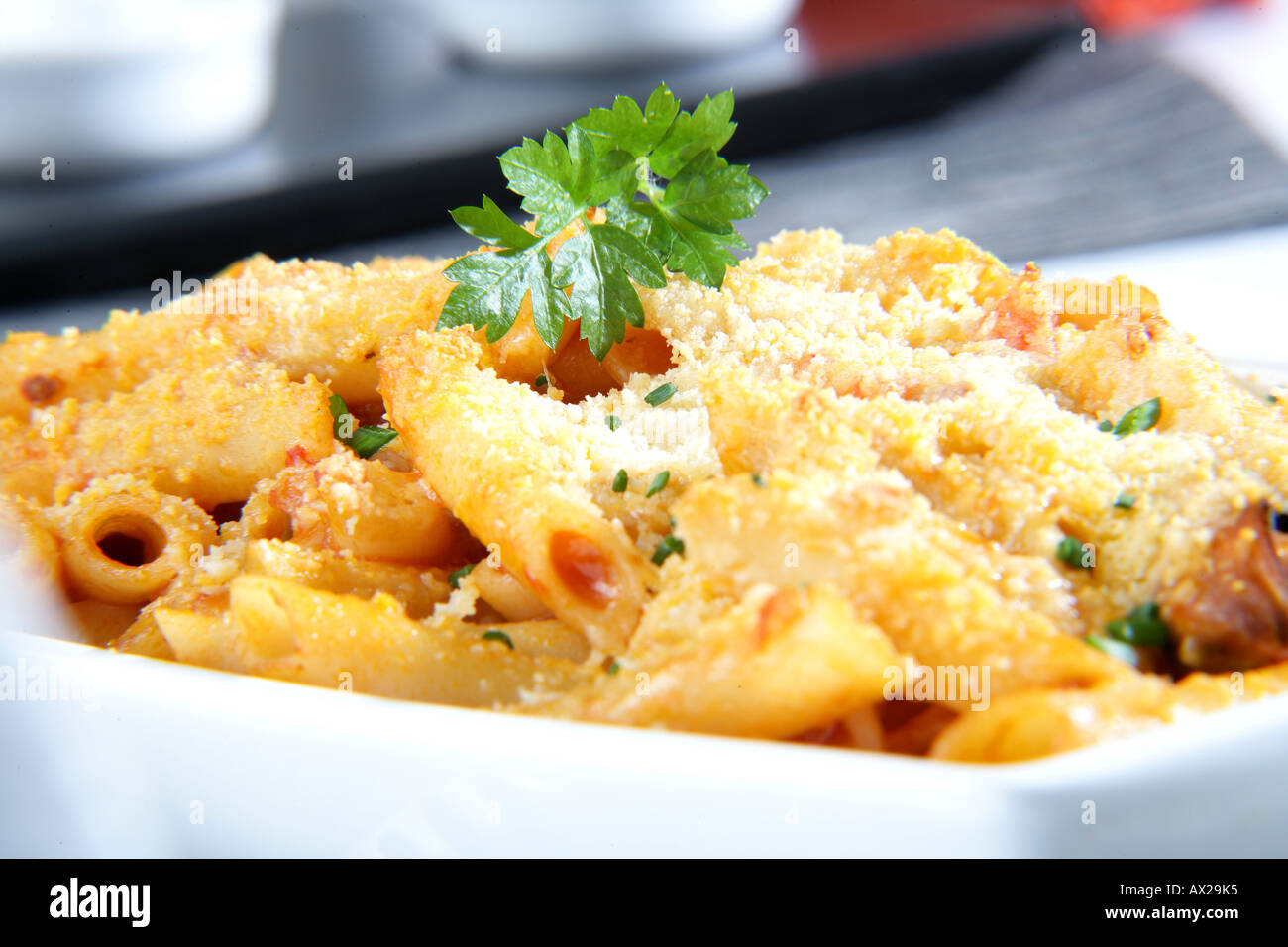 Penne gratinate con pesce e frutti di mare di formaggio grattugiato Foto Stock