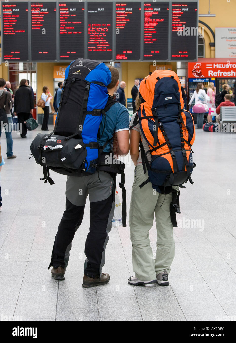 Due viaggiatori con lo zaino in spalla alla stazione ferroviaria information board Foto Stock