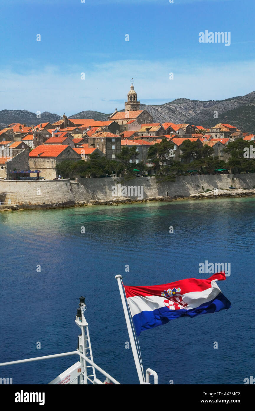 Barca con bandiera nazionale avvicinandosi Korcula nel mare Adriatico Croazia Foto Stock
