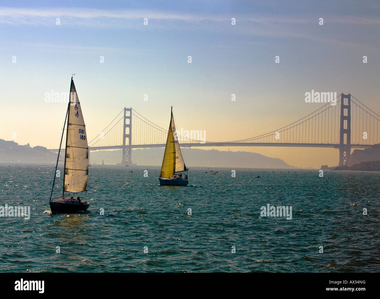 Barche a vela nella Baia di San Francisco, Stati Uniti d'America, di fronte al Golden Gate Bridge come il sole tramonta Foto Stock