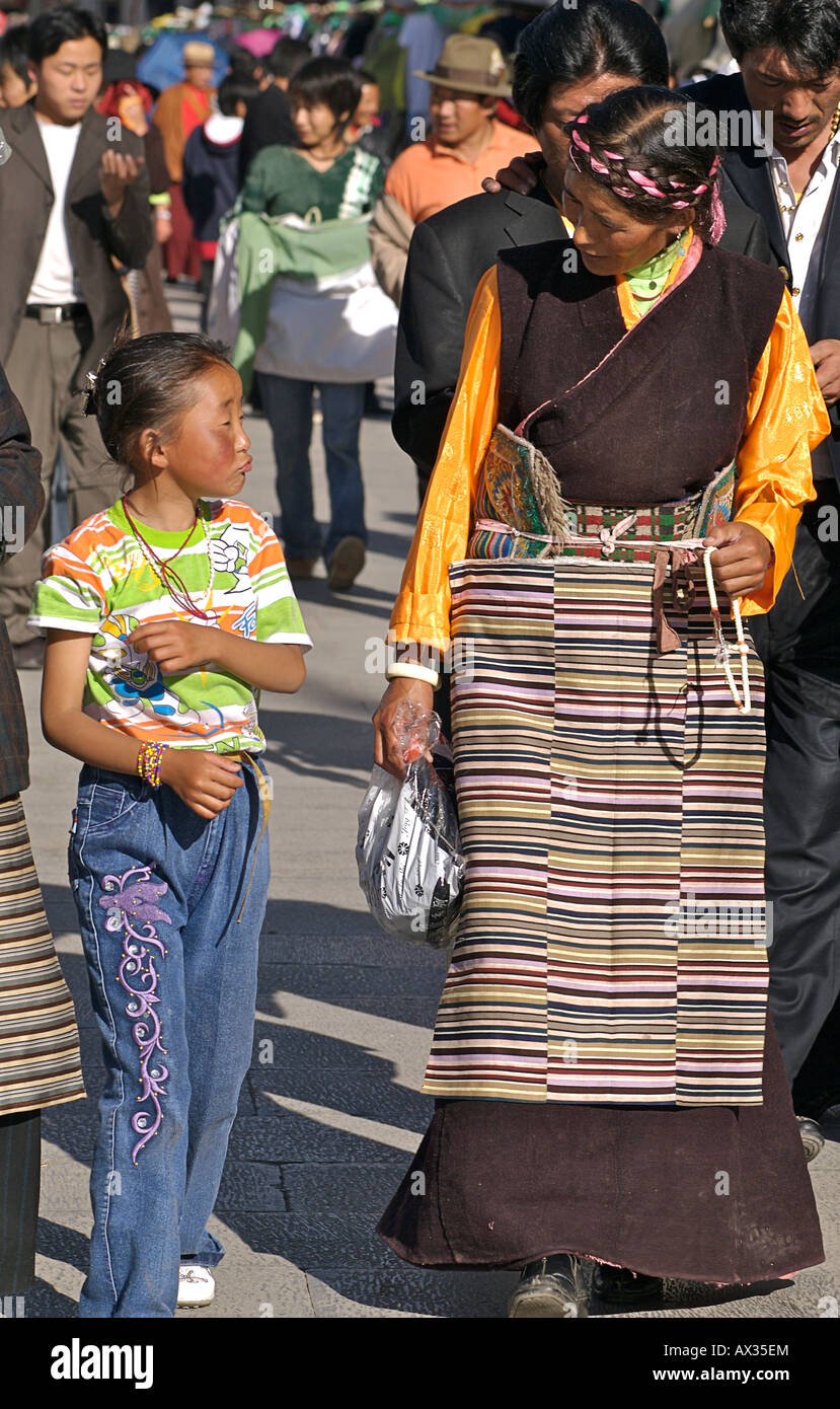 Madre tibetana in tradizionale stile di vestiti a piedi con sua figlia vestito in abito moderno. Lhasa, in Tibet Foto Stock