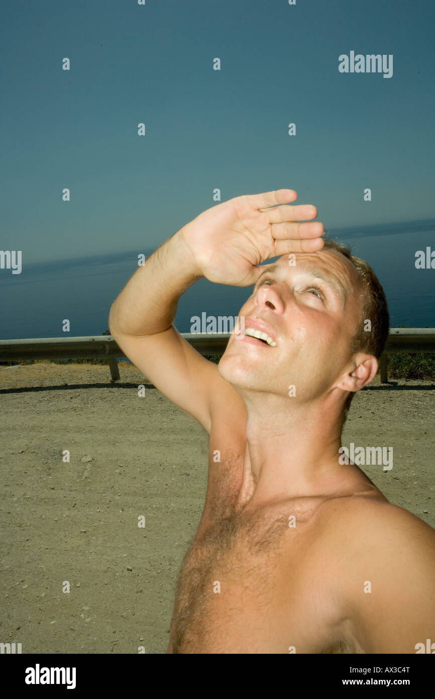 Giovane uomo che copre la sua gli occhi e guarda il sole Foto Stock