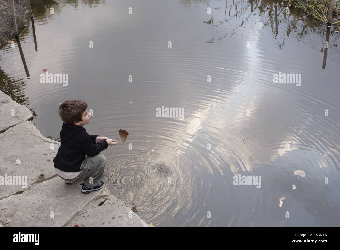 Poco boy holding leaf accanto all'acqua. Foto Stock