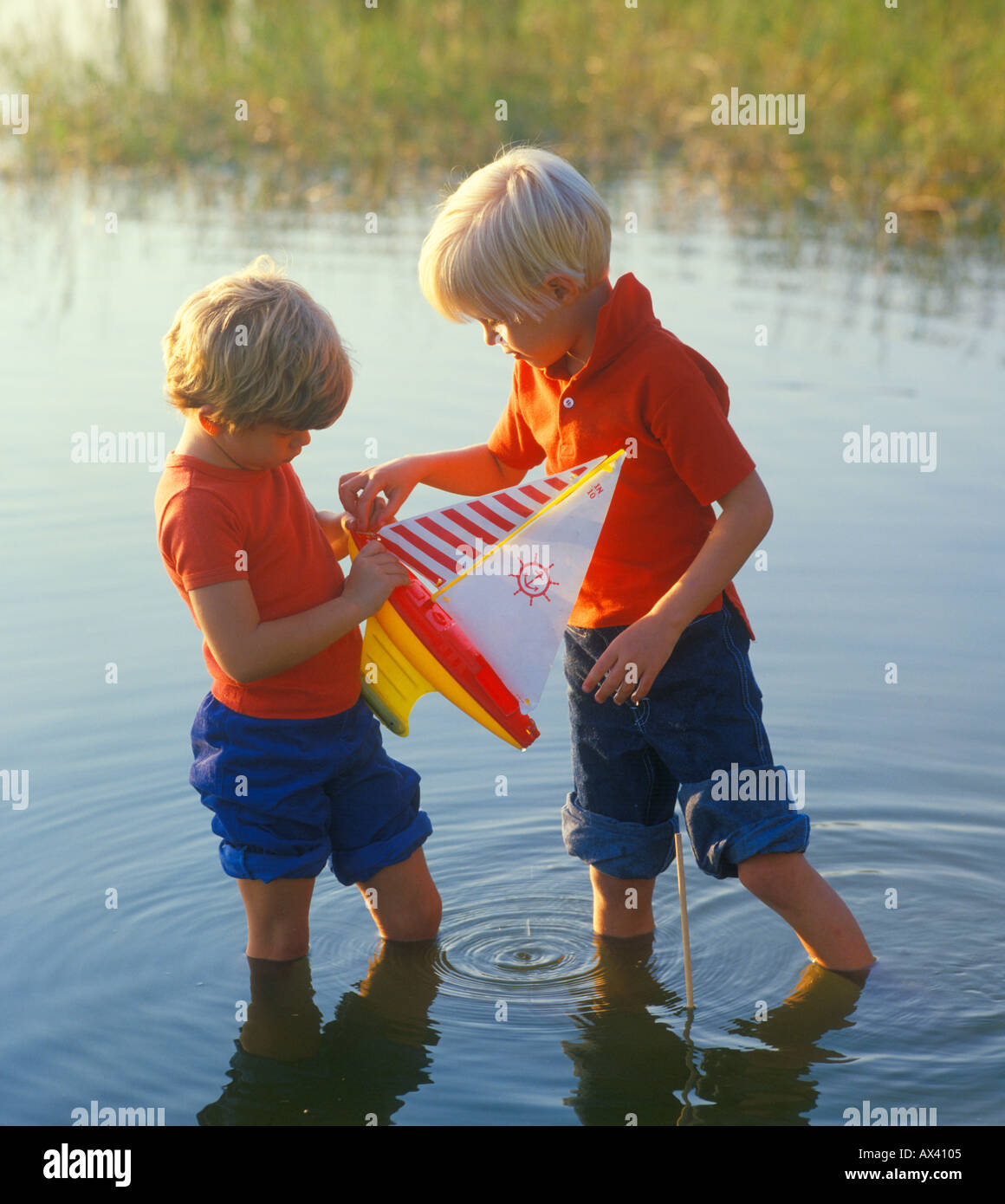 Un ragazzo e una ragazza gioca con il giocattolo in barca a vela nel lago Foto Stock