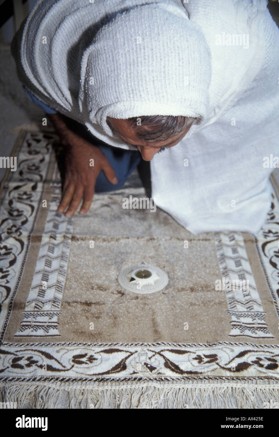 Un musulmano prega verso la Mecca utilizzando una bussola sul suo tappeto  da preghiera Foto stock - Alamy