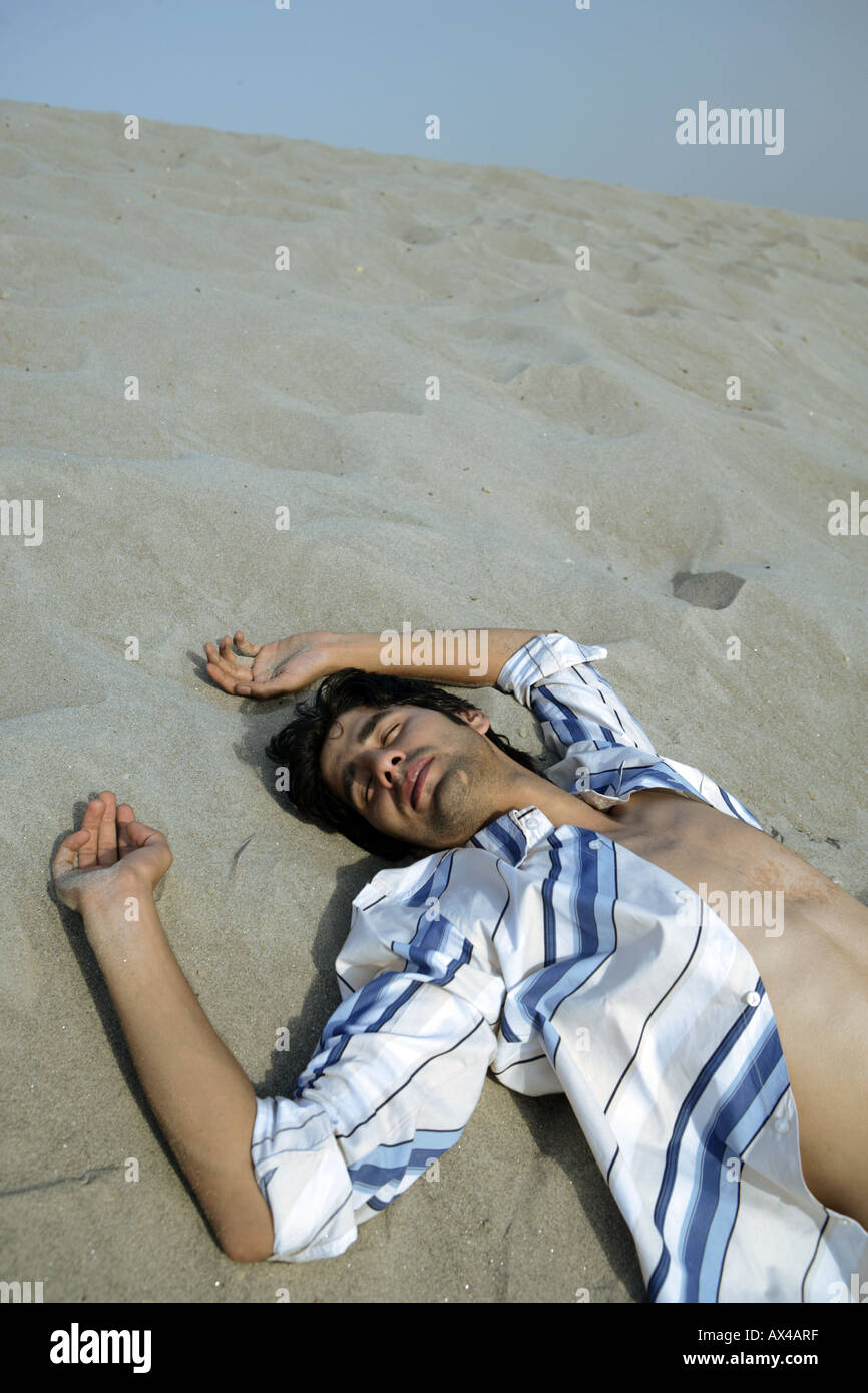 Uomo di dormire sulla sabbia in un deserto Foto Stock